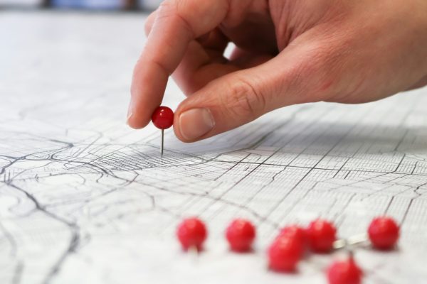 Close up photo of a hand putting pins in a map