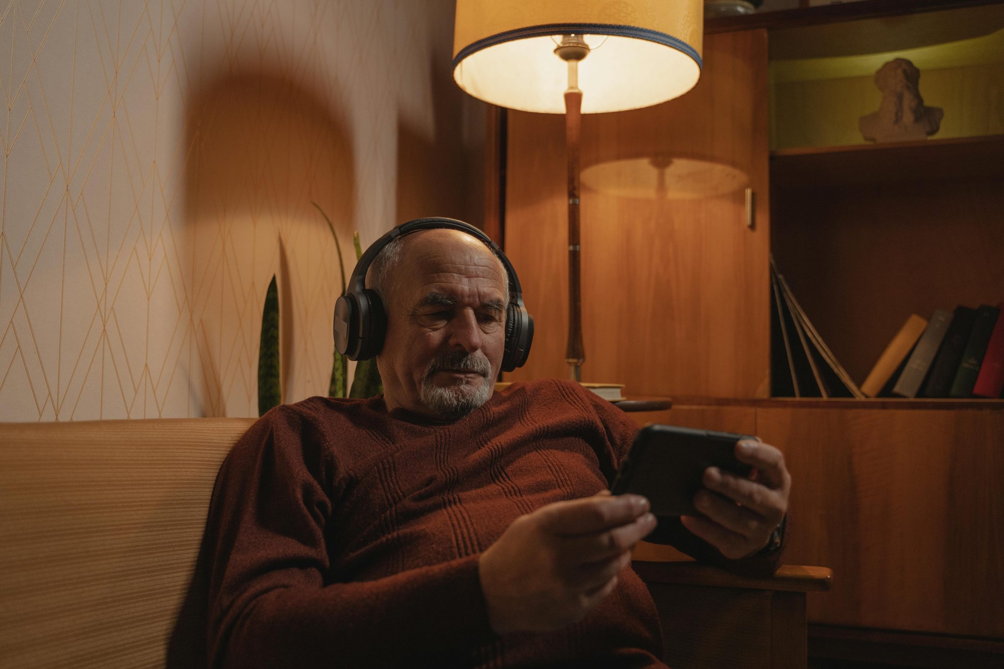 Man watching his phone, listening to content with headphones.