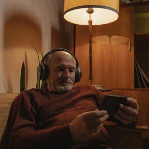 Man watching his phone, listening to content with headphones.