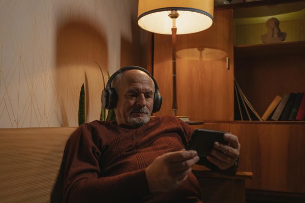 Man watching his phone, listening to content with headphones.