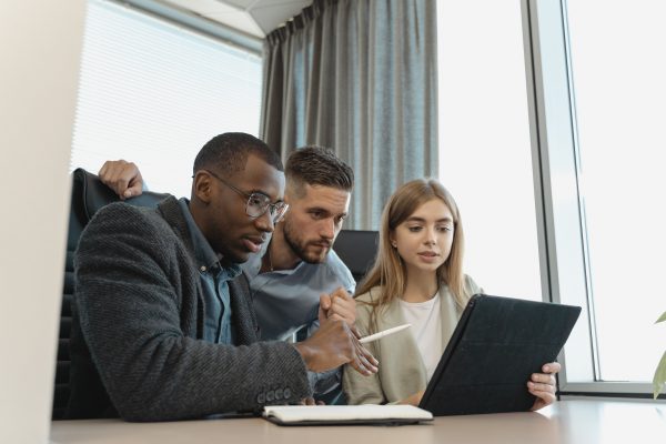 A black male, a white male and a white woman all looking at a screen intently